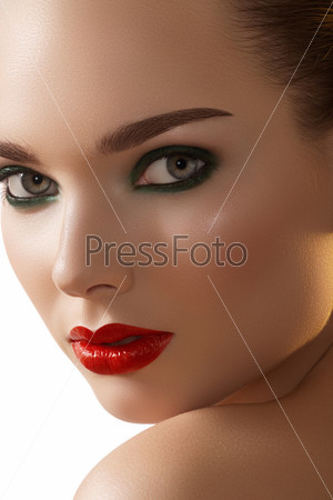Close-up portrait of beautiful woman\'s purity face with bright red lips makeup and dark green smoky-eyes make-up. Sexy model with clean shiny skin