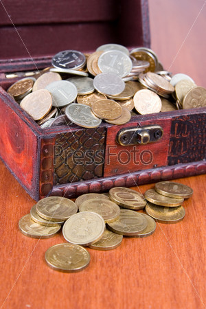 Open chest with coins on a wooden surface close-up
