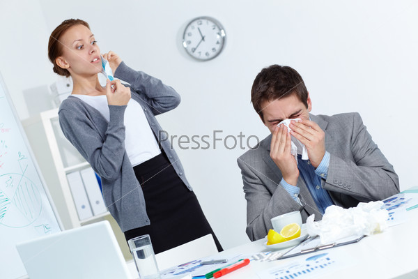 Image of businessman sneezing while his partner looking at him with fright in office