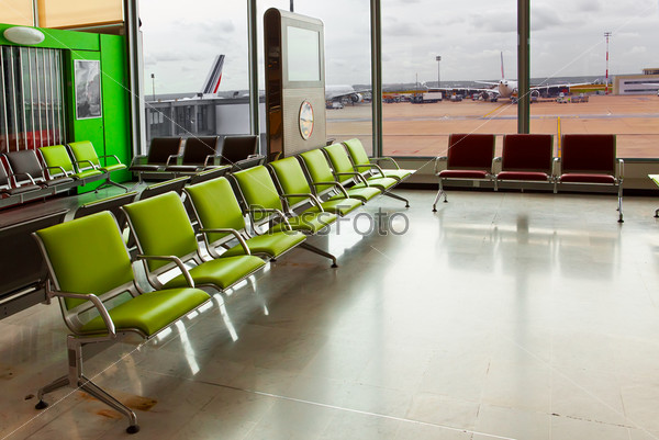 Empty armchairs in hall of expectation of airport and plane behind window , stock photo