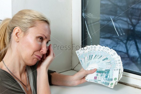 The housewife cries and counts money for repair of a double-glazed window w