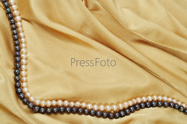 Gold silk background with pearl necklace on it, stock photo
