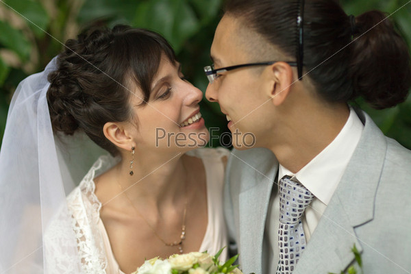On the day of the wedding the young bride and groom in the garden close to each other for a gentle kiss