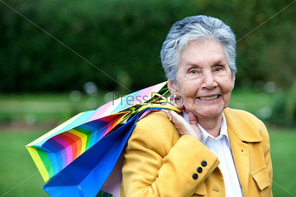 Beautiful old lady shopping with paper bags outdoors