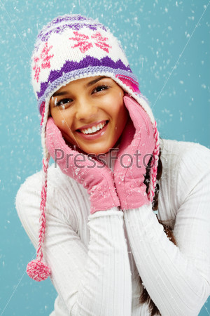 Portrait of pretty woman in pink gloves and knitted winter cap looking at camera with smile