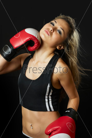 Beautiful young woman in boxing gloves at black background