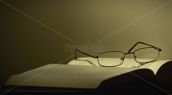 Glasses and a book on a dark background, stock photo