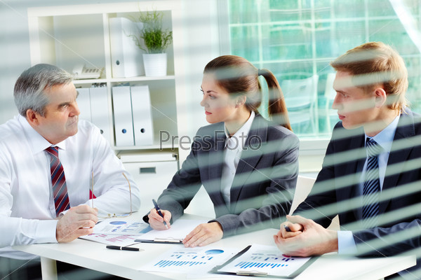 Portrait of busy people discussing new working plan at meeting in office