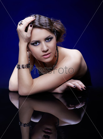 portrait of young beautiful brunette woman in jewellery at mirror table
