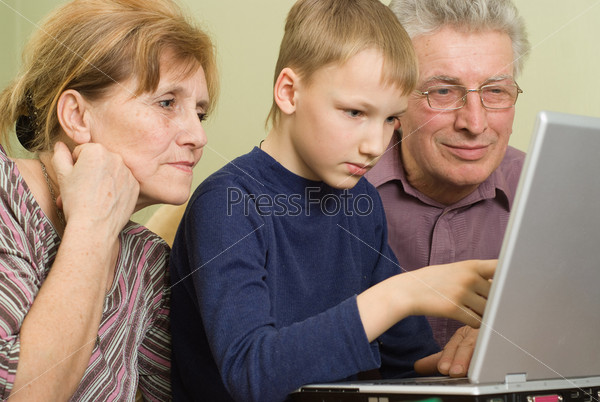 grandfather and grandmother with her grandson play in a notebook