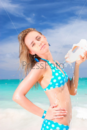 Woman pouring water from shell on caribbean beach