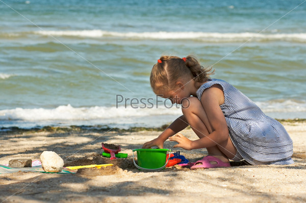 Small girl play with sand near sea