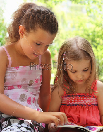 Children reading the book in summer park