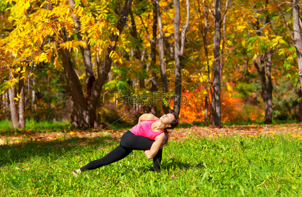 Woman exercises in the autumn forest yoga parivrita parshvakonasana pose