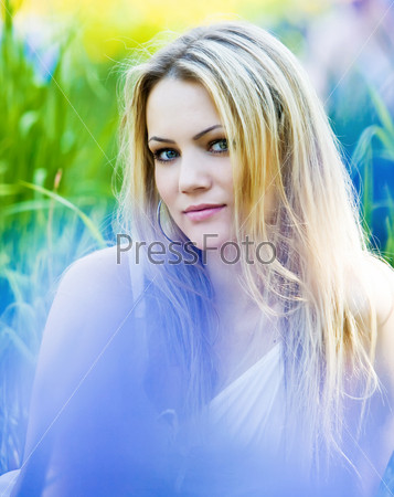 Outdoor portrait of beautiful young smiling woman with long white hair in sunny summer day