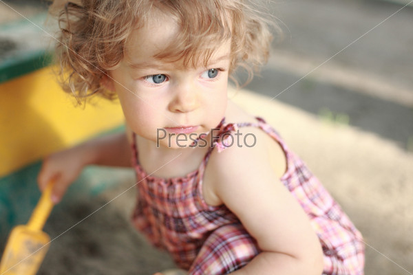 Child plays in sandpit - shallow depth of field, stock photo