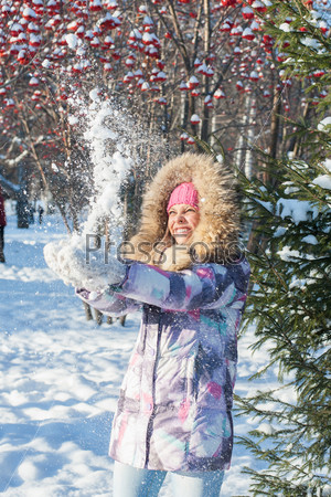 Young beautiful woman play with snow in winter park