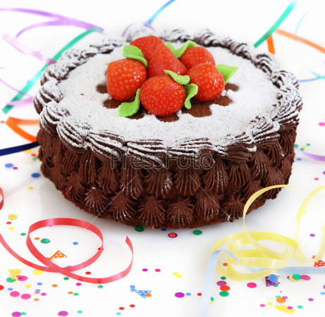 Chocolate cake decorated with strawberry with streamers over white background