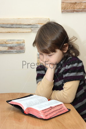 Маленькая девочка читает Библию