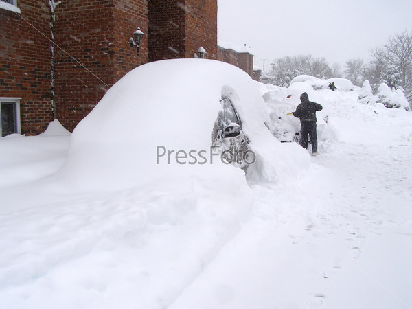 Мужчина откапывает автомобиль из-под снега