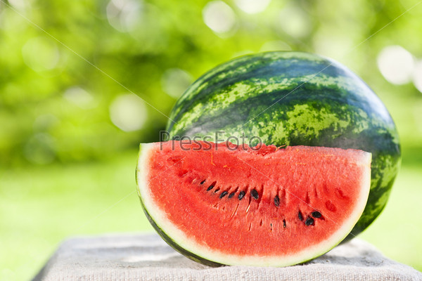 Fresh juicy watermelon against natural green background in spring park