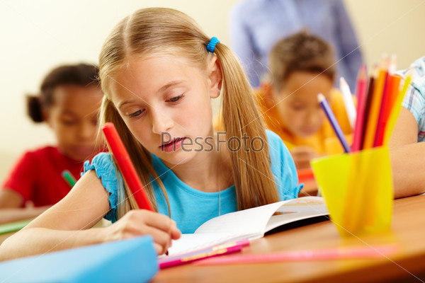 Portrait of lovely girl drawing with colorful pencils at lesson