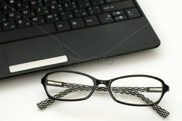 Business glasses near a laptop keyboard