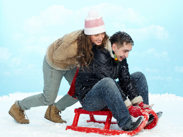 Portrait of happy couple tobogganing during winter vacation