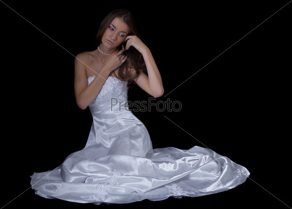 beatiful young woman in wedding dress on black sits and\
ponders an touches her hair