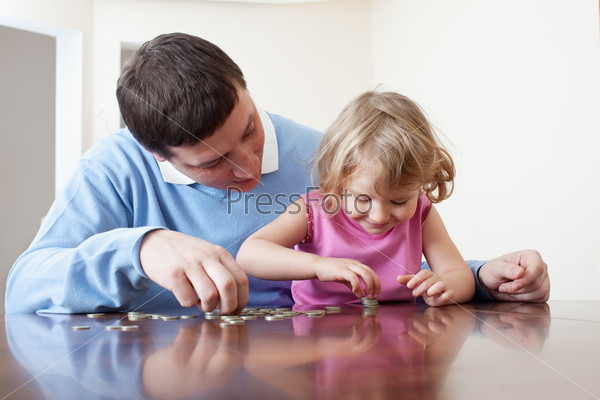 Father and daughter puts coins. Father teaches the child Finance