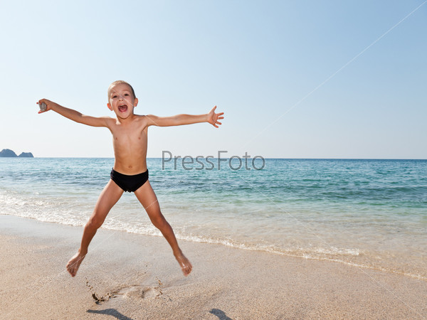 Little smiling child boy jumping on sea sand beach