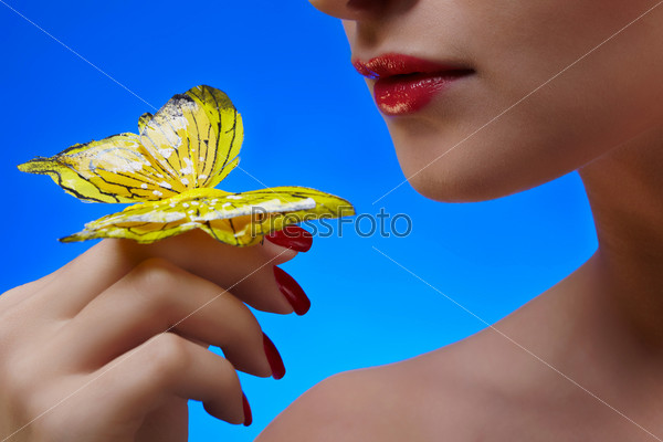 close-up of lower part of beautiful girl\'s face turning to artificial butterfly on her finger