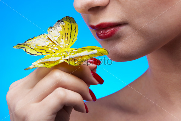 close-up of lower part of beautiful girl\'s face turning to artificial butterfly on her finger