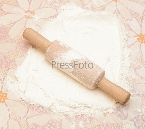 Classic wooden rolling pin with freshly prepared dough and dusting of flour.