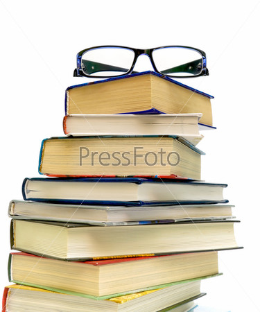 glasses at a pile of books on white background close-up