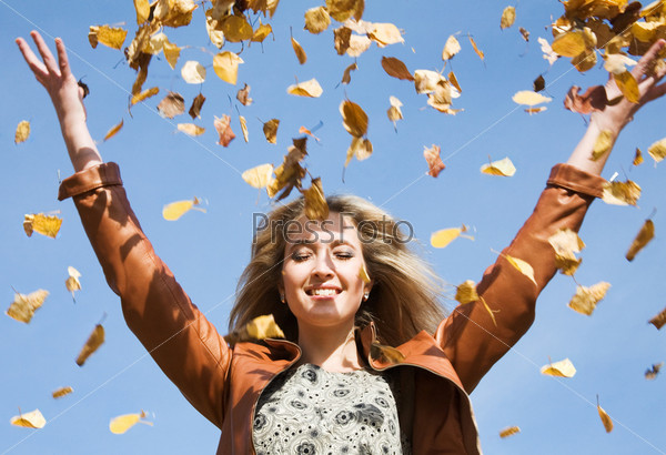 Attractive woman throw up autumnal leaves