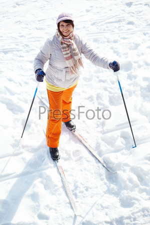 Portrait of attractive middle aged woman looking at camera while skiing outside