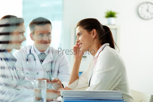 Portrait of confident practitioners consulting patient in hospital