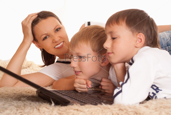 mom with his sons is on the carpet with laptop