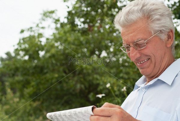 Пожилой мужчина в очках читает газету
