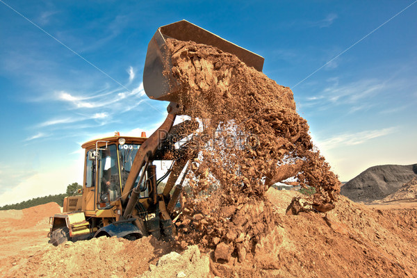 Wheel loader unloading soil at construction site