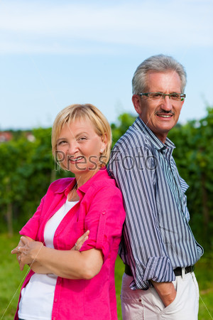 Visibly happy mature or senior couple outdoors back to back having a walk