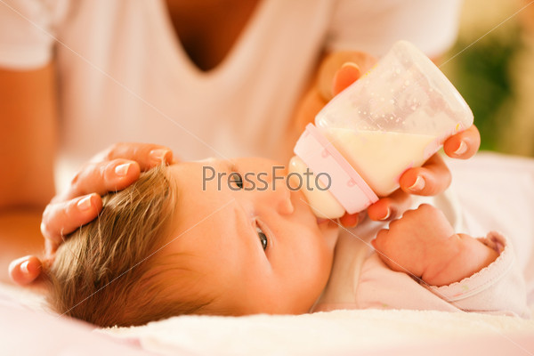 Mother is feeding her baby with a bottle; very tranquil scene