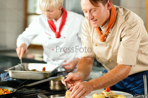 Два повара, мужчина и женщина, готовят на кухне