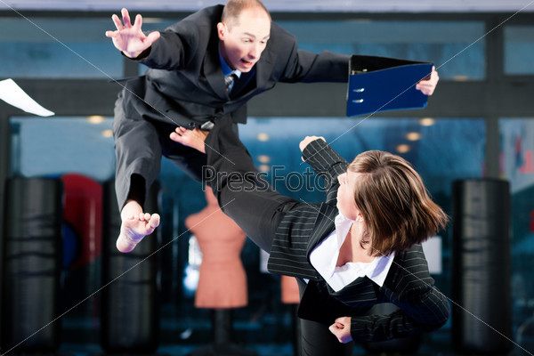 Business concept - People in a gym in martial arts training exercising Taekwondo, both wearing suits