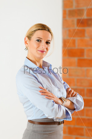 Realtor standing with folded arms in an empty apartment