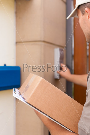 Postal service - delivery of a package; the postman is standing in front of the door and rings the bell