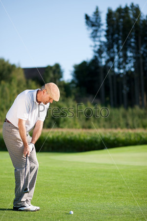 Senior golfer doing a golf stroke, he is playing on a wonderful summer afternoon, stock photo
