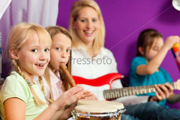 Family - Children and mother - making music; they are practicing playing guitar, bongo and flute