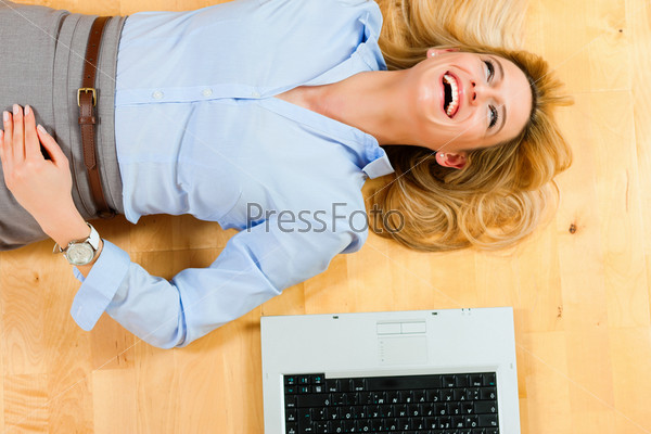 Businesswoman is lying on the floor at home relaxing, a laptop beside her